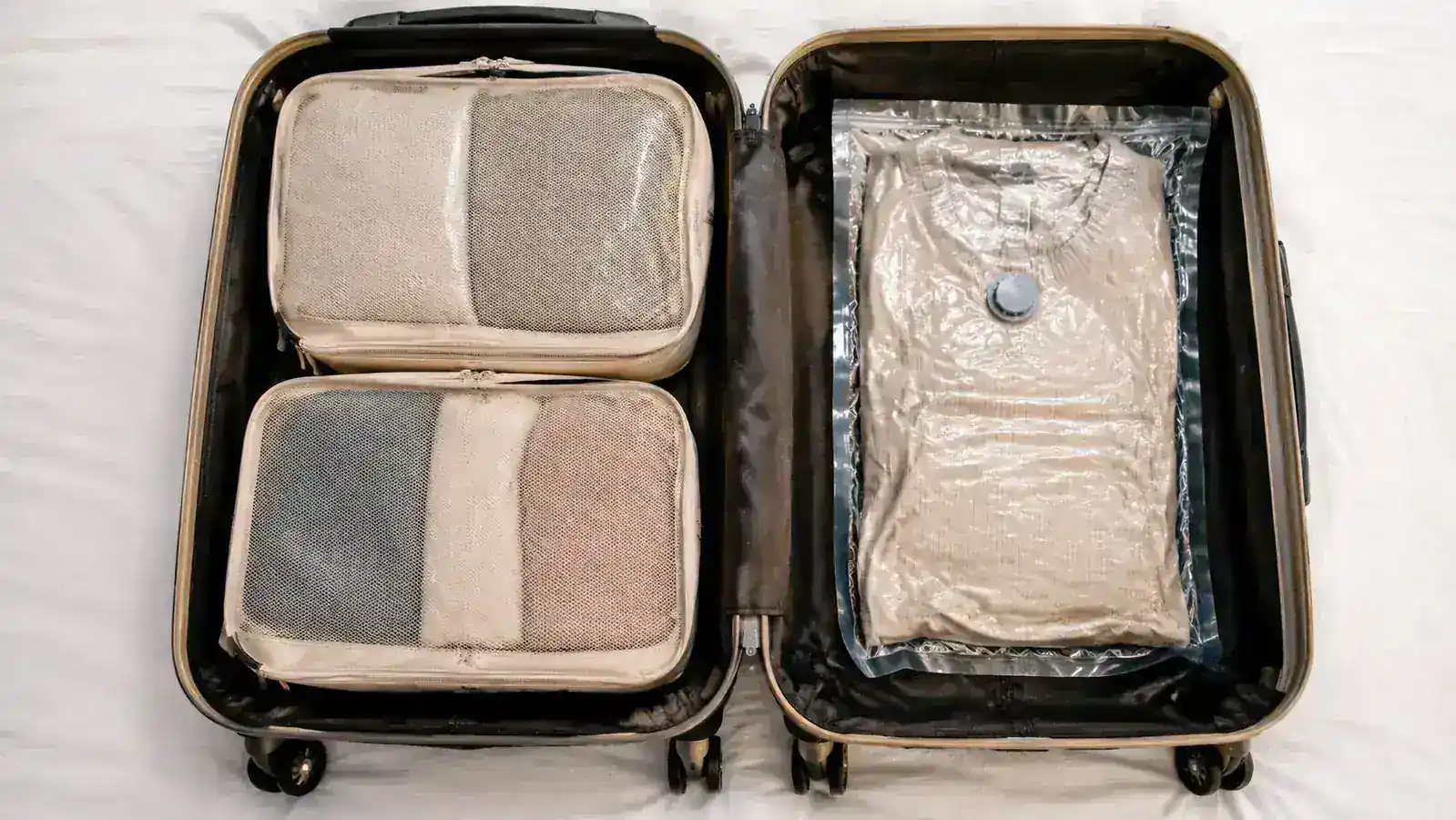Packing cubes neatly stacked next to a rolled vacuum bag inside an open carry-on suitcase, showing a side-by-side packing comparison