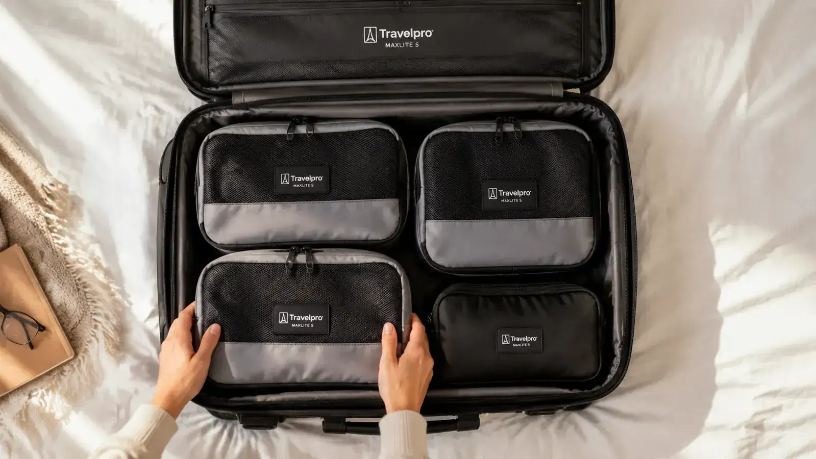 Overhead view of Travelpro Maxlite 5 open on a bed, packed with packing cubes and a toiletry bag inside
