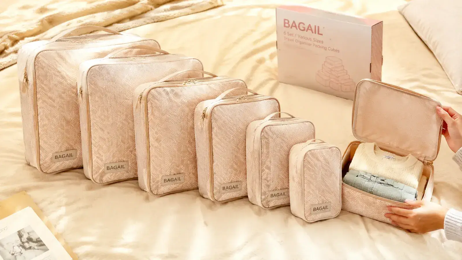 Six BAGAIL packing cubes laid flat on a bed in different sizes showing the full 8-set variety