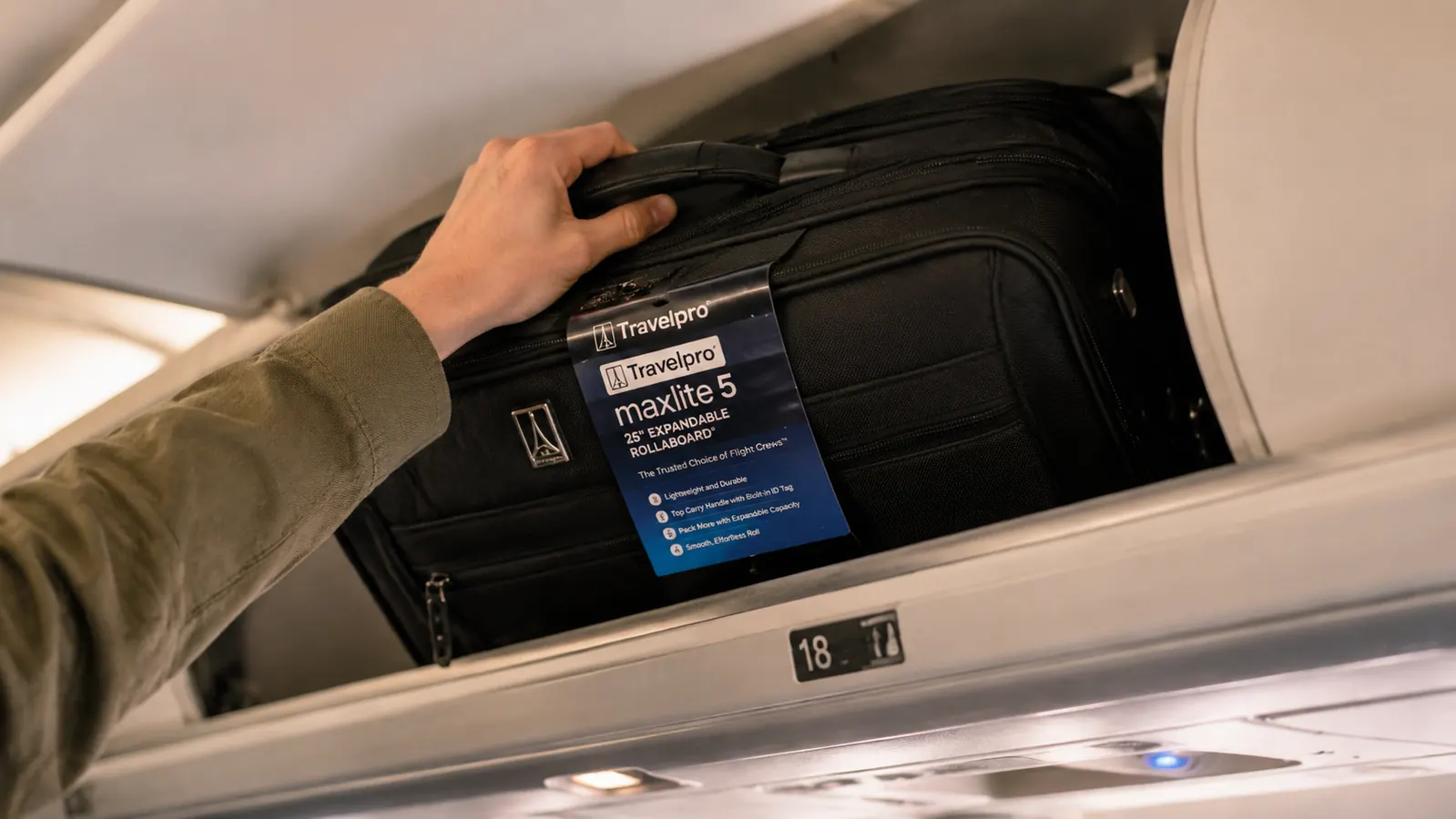 Person gripping the Travelpro Maxlite 5 top carry handle while loading it into an overhead bin